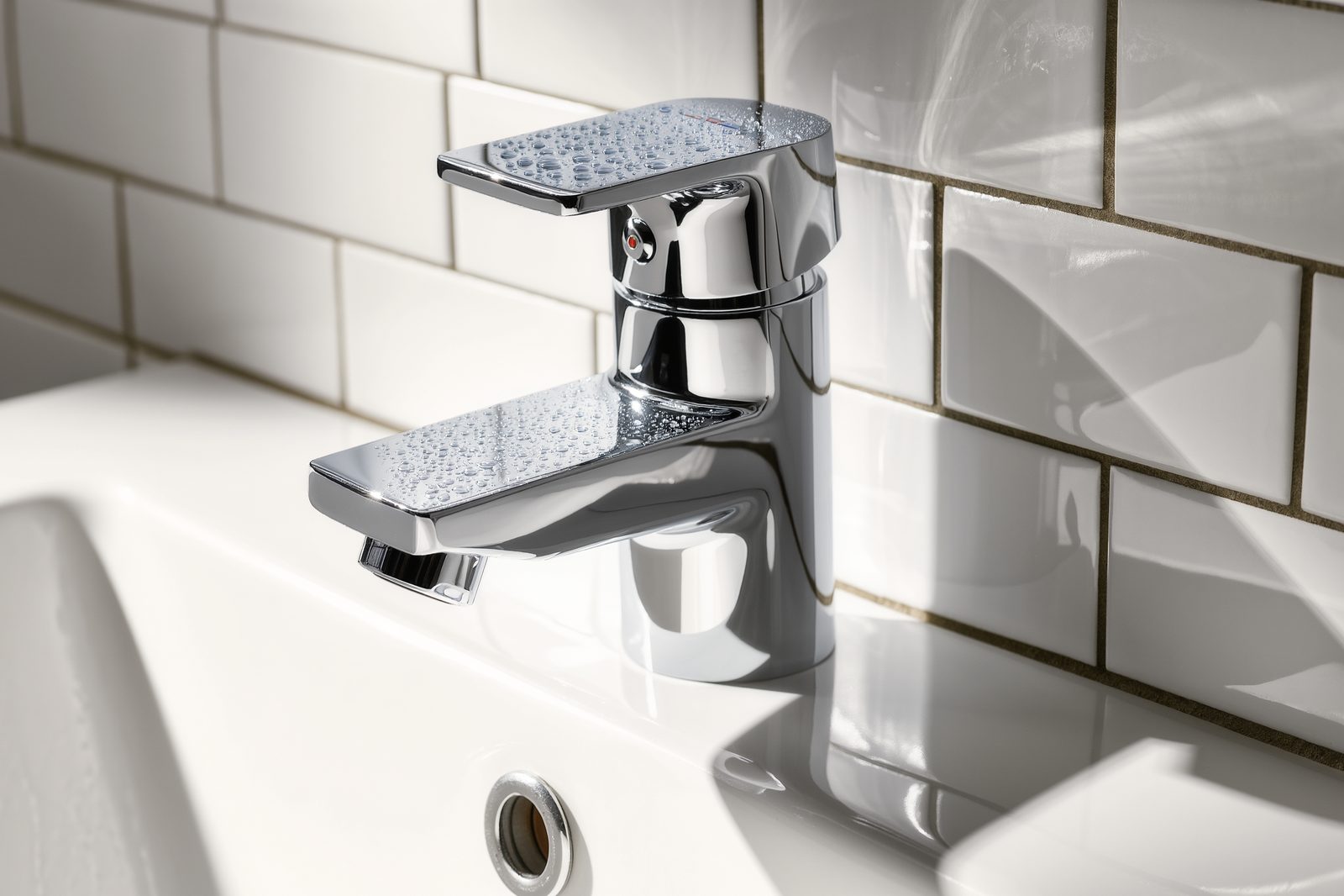 Gleaming chrome mixer tap on white subway tile